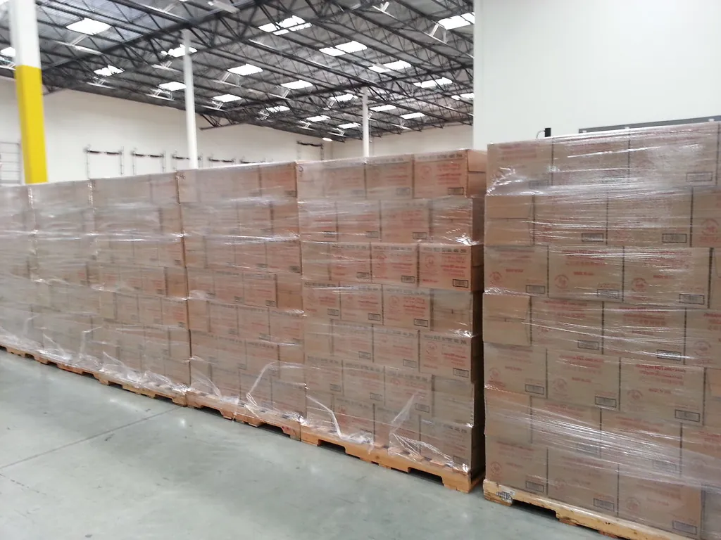 Tarimas cargadas y emplayadas en columna, alineadas en un almacén listas para envío