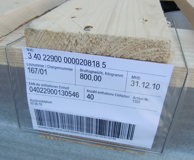 Etiqueta logística con códigos GS1-128 dentro de un portaetiquetas tamaño A6 en una tarima