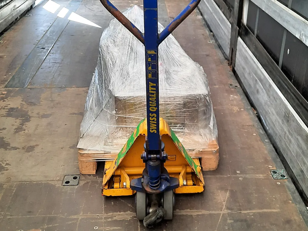 Patín hidráulico metido en una tarima de madera con carga emplayada dentro de un camión