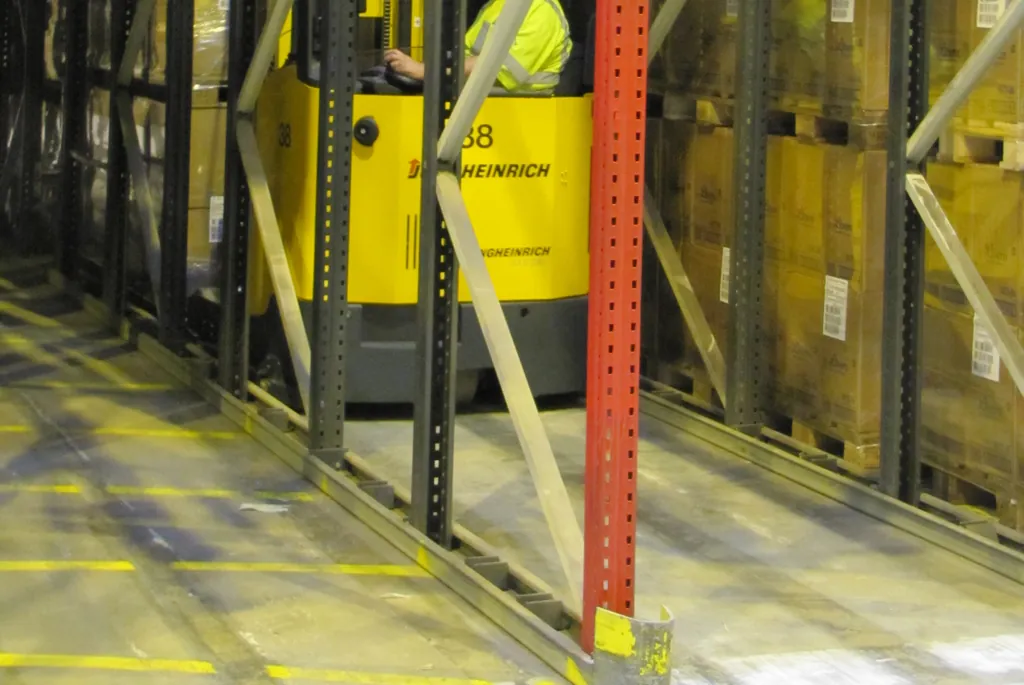 Reach truck trabajando en un pasillo angosto entre racks con tarimas cargadas